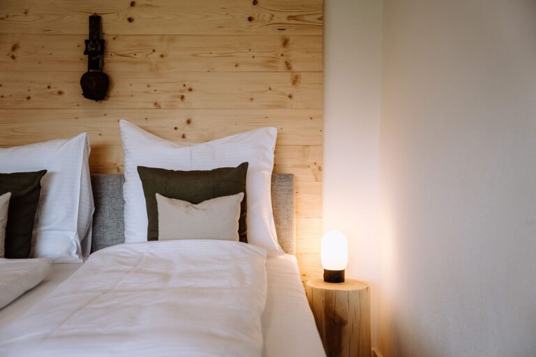 Home Staging Starnberg Ferienwohnung Bett mit Dekorationselementen wie Kuhglocke und Lampe